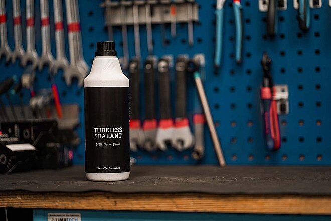 Eine Flasche mit weissem Inhalt steht auf einer Werkbank.