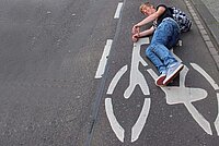 Das Veloweggesetz ist seit 1. Januar 2023 in Kraft. Ein Mann liegt auf einem Velosignet am Boden. 