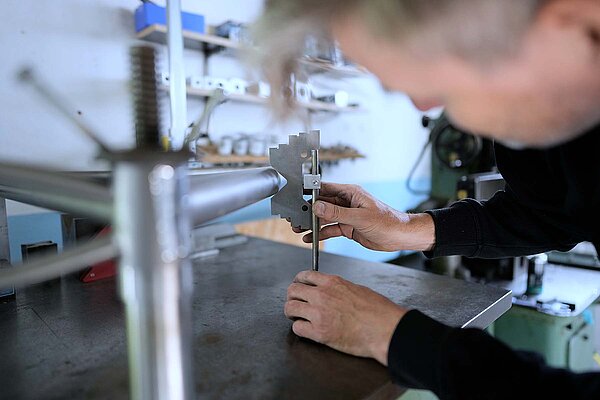 Mag es, wenn die Dinge passen: Rahmenbauer Stefan Süess. Ein Mann arbeitet an einem Tisch an einem Fahrradrahmen aus Titan.