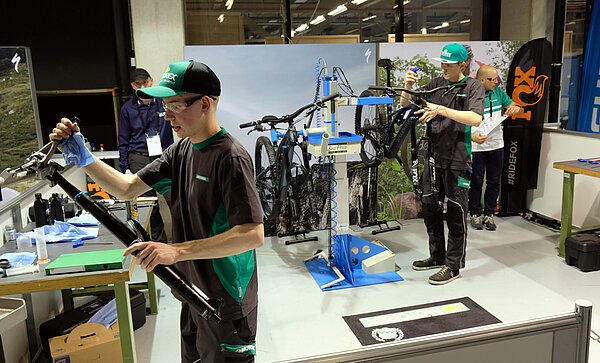 Junge Männer mit Baseball-Caps arbeiten an Fahrrädern.
