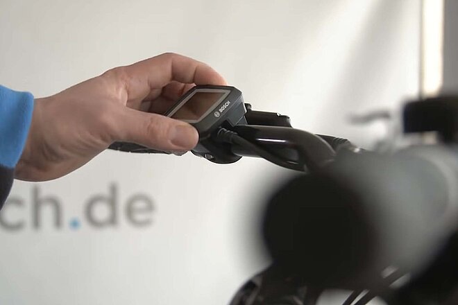 Eine Hand bedient den Boardcomputer eines E-Bikes.