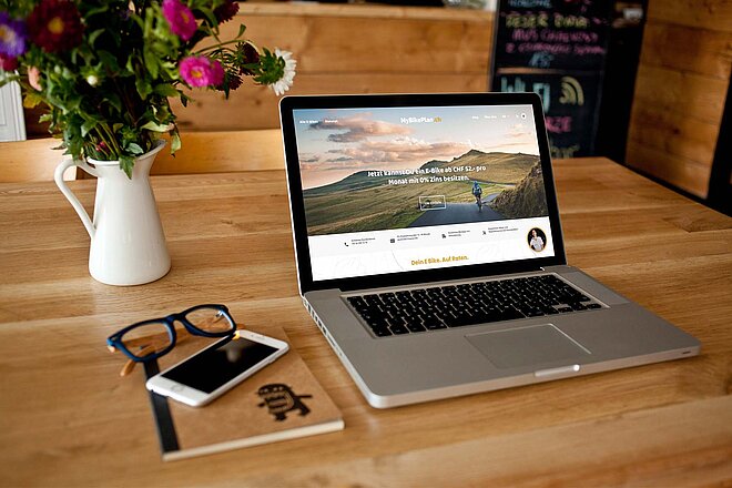 Tisch mit Blumenvase und Laptop und Smartphone