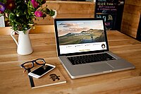 Tisch mit Blumenvase und Laptop und Smartphone
