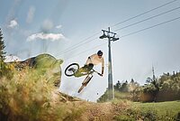 Biketrail Weissenstein. Ein Bike springt mit seinem Bike über einen Hügel.