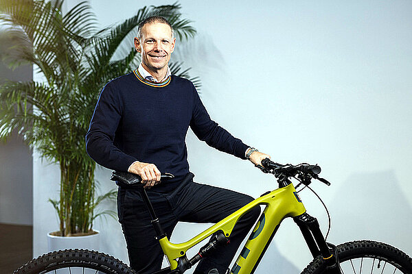 TVS Motor übernimmt 100 Prozent von M-Way. Ein Mann steht hinter einem E-Mountainbike.