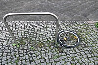 An Velobügel gekettetes Velorad liegt auf Pflastersteinen.
