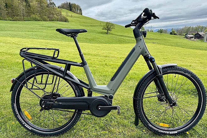 Test Moustache J E-Bike. Ein Elektrovelo steht auf einer grünen Wiese.