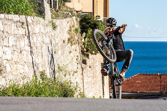 Der codice della strada besagt, dass in Italien alle Velos mit Licht ausgerüstet sein müssen. Ein Biker fährt auf dem Hinterrad in Finale Ligure. 