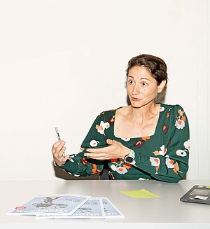 Eine Frau sitzt an einem Besprechungstisch.