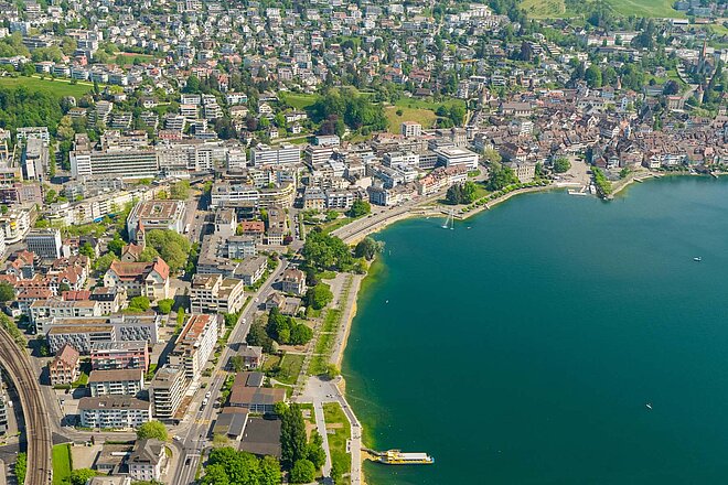 Kanton Zug Planung Veloweggesetz. Luftaufnahme einer Stadt am Zugersee.