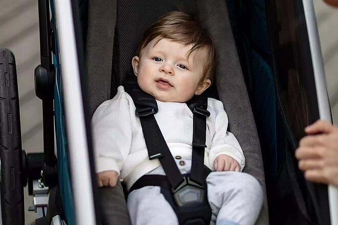 Kleinkind sitzt in einem Fahrradanhänger.
