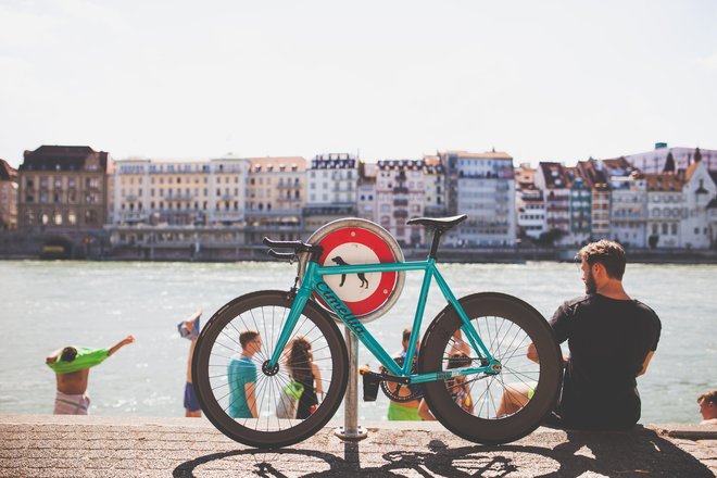 Ein Mann sitzt mit seinem Fahrrad am Rheinufer in Basel.