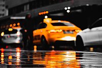 Mit dem Taxi durch Wien. Autos spiegeln sich auf dem nassen Asphalt.