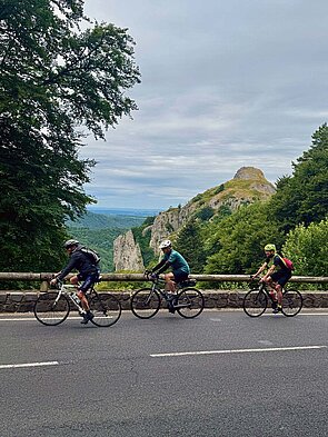 Rennradfahrer auf einer Strasse. Im Hintergrund Berge.