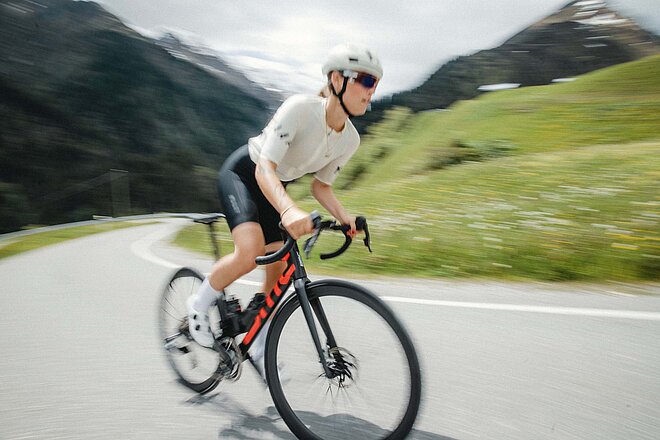 Eine Rennradfahrerin mit weissem Tricot und weissem Helm.