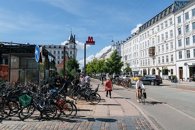 Metrostation in Kopenhagen, vor der viele Fahrräder auf dem Trottoir stehen.