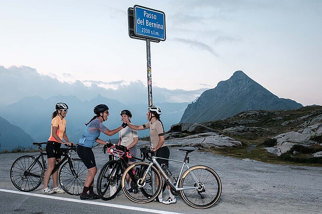 Am Event «Las Ciclistas» sind Frauen unter sich. Frauen mit Rennrädern stehen unter dem Schild eines Alpenpasses.