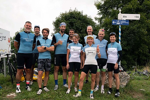 Bergzeitfahren Buchenegg Ostwand. Frauen und Männer stehen mit Velotrictos und Velohosen auf einer Wiese. 