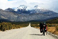 E-Bike Fahrer kämpfen noch immer gegen Vorurteile an. Ein Tourenrad steht auf einer Landstrasse, im Hintergrund Berge.