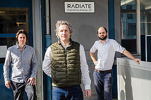 Radiate Engineering & Design. Drei Personen stehen vor einer Betonwand.