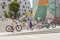 Kinder stehen mit Kinderfahrrädern auf einer grossen Treppe.