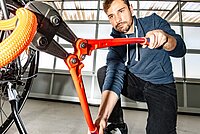 Fahrradschloss Test. Die besten Veloschlösser. Ein Mann knack ein Fahrradschloss mit einer Zange.