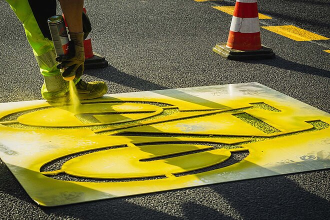 Die Veloinfrastruktur hinkt der Entwicklung hinterher. Es braucht mehr Platz für Velofahrende im Strassenverkehr. (Foto: Quimby / Peter Broytman, CC0 1.0) Fahrradsignet wird auf Boden gesprüht.