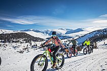 Eine Gruppe von Velofahrern ist mit Fatbikes im Schnee unterwegs.