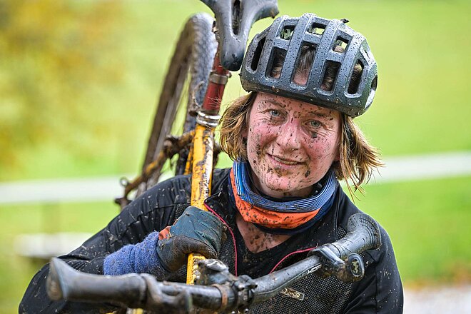 Eine Radfahrerin mit Dreck verspritztem Gesicht.