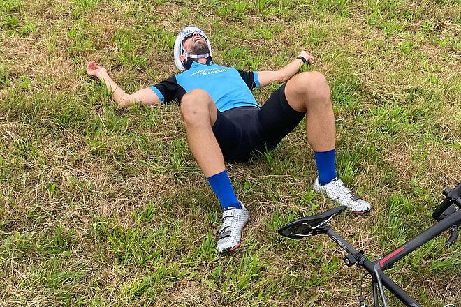 Bergzeitfahren Buchenegg Ostwand. Ein Mann liegt erschöpft im Grass.