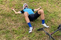 Bergzeitfahren Buchenegg Ostwand. Ein Mann liegt erschöpft im Grass.