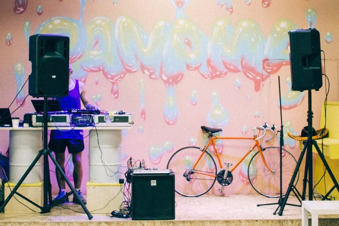 DJ steht for Wand mit Graffiti, am Rand des Bildes steht ein Fahrrad