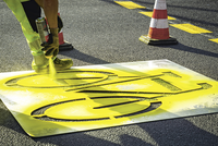Ein Arbeiter sprüht ein gelbes Velossymbol auf die Strasse