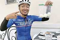 UCI Gravelbike WM 2022. Eine Frau hält einen Beutel mit Eiern in der Hand.