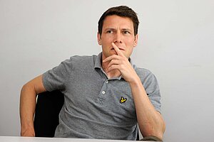 Ein Mann sitzt auf einem Bürostuhl.