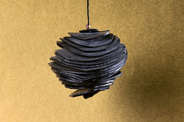 Weihnachtliches Ornament, Christbaumkugel aus Veloschlauchrondellen vor goldenem Hintergunrd