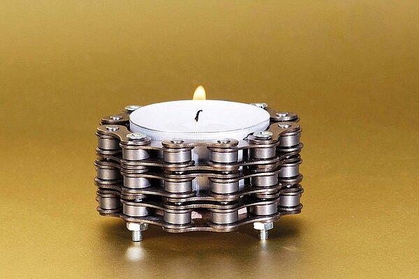 Teelicht aus Velokette vor goldenem Hintergund.