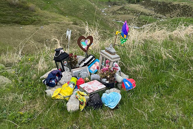 Kerzen und Erinnerungsstücke stehen an einer Unfallstelle. 