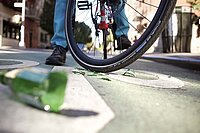 Tipps damit Fahrradreifen nicht die Luft ausgeht. Scherben auf einer Strasse vor einem Fahrrad.