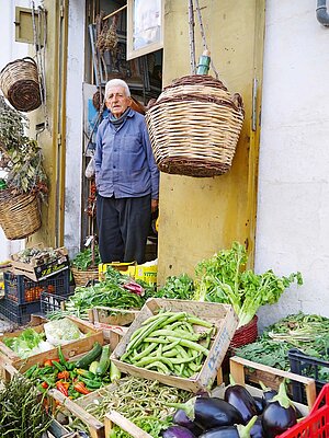 Fahrradreise Apulien. Ein Mann steht vor Kisten mit Gemüse.