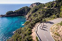 Radfahrer auf einer Küstenstrasse. Im Hintergrund das Meer.