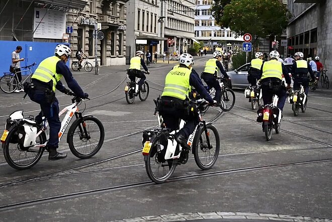 Repression an der Critical Mass in Zürich. Polizisten in Leuchtwesten fahren auf E-Bikes in der Stadt Zürich.