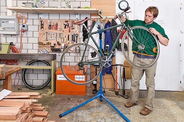 Ein Mann schraubt im Keller an einem Fahrrad