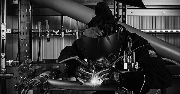 schwarz weiss foto das eine Person bei Schweissarbeiten zeigt