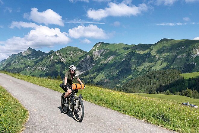 Lieber nicht am selben Abend wieder zurück: Das Gepäck für Mehrtages-Etappen lässt sich bestens am Velo befestigen. (Foto: Ralph Bensberg) Eine Radfahrerin radelt mit ihrem Bikepacking-Bike in den Bergen