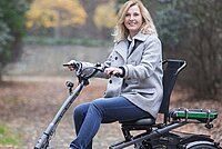 blonde Frau fährt auf Dreirad auf einem Waldweg