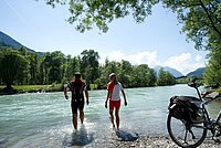 Radfahrer kühlen die Beine in einem Fluss ab.