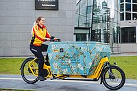 Basel Stadt Wirtschaft unter Strom Subventionen für Cargobikes. Eine Lieferdienstmitarbeiterin fährt auf einem Lastenrad.