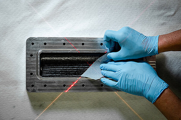 Radiate Engineering & Design. Hände in chirurgischen Handschuhen halten eine Stück Carbon.