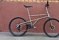 Helix Faltvelo im Test. Edles Faltrad aus Titan steht vor einer roten Mauer.